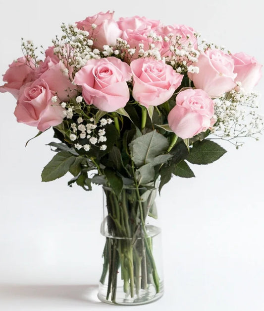 Bouquet of pink roses with baby's breath in a clear vase on a white background
