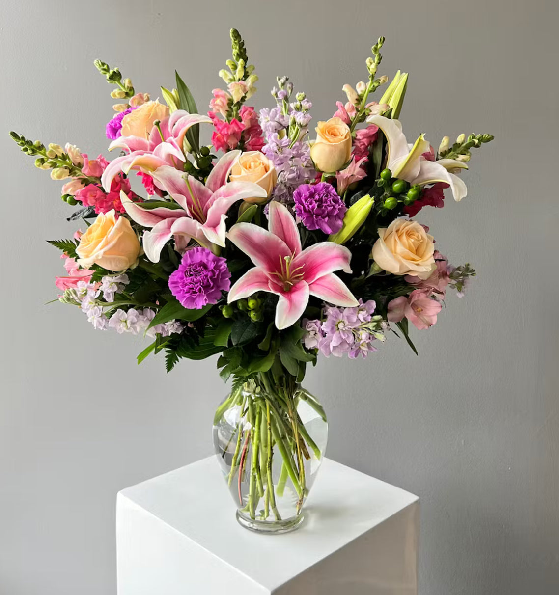 Bouquet of colorful flowers in a clear vase on a gray background