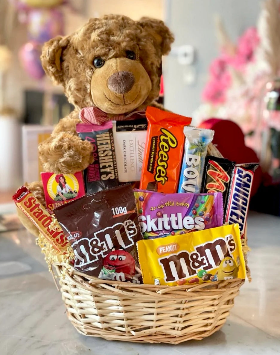 Teddy bear and candy basket with various candies in a wicker basket.